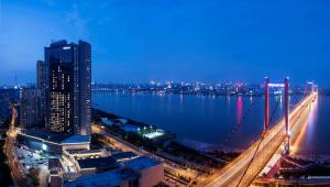 uma vista para uma cidade com uma ponte sobre a água em Hilton Wuhan Yangtze Riverside em Wuhan