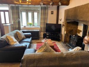 a living room with two couches and a television at 17th Century Cottage, Log Burner & Hidden Garden in Oakworth