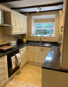 a kitchen with white cabinets and a sink and a window at 17th Century Cottage with Hidden Garden in Steeton