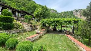 a garden with a pergola with a table and chairs at Milkovata Guest House in Koshov