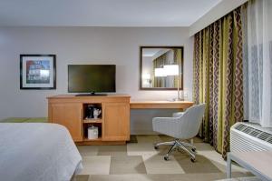 a hotel room with a bed and a desk with a television at Hampton Inn Boston - Westborough in Westborough
