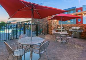 a patio with tables and chairs with red umbrellas at Home2 Suites By Hilton Gonzales in Gonzales