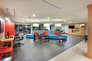 a lobby with a blue couch and tables and chairs at Home2 Suites By Hilton Gonzales in Gonzales