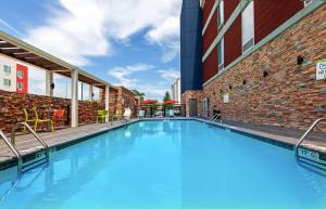 een groot zwembad naast een bakstenen gebouw bij Home2 Suites By Hilton Gonzales in Gonzales