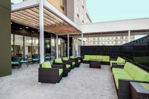 a patio with green chairs and tables in a building at Home2 Suites By Hilton Austin Airport in Austin