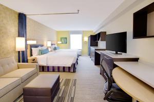 Home2 Suites By Hilton Chicago Schaumburg في شامبورغ: غرفه فندقيه بسرير واريكه