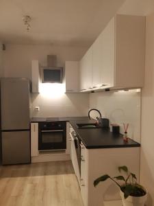 a kitchen with white cabinets and a black counter top at Apartament Cztery Pory Roku Gdańsk in Gdańsk