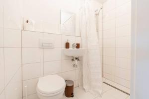 Baño blanco con aseo y lavamanos en Stilvolles Apartment für 4 Pers. en Bremen