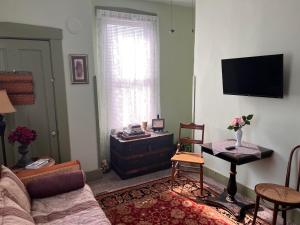 ein Wohnzimmer mit einem Sofa, einem Tisch und einem TV in der Unterkunft Mansion on The Mile B&B in Indianapolis