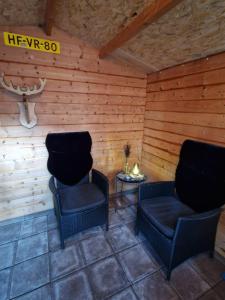 two chairs and a table in a room with wooden walls at Chalet in Putten in Putten