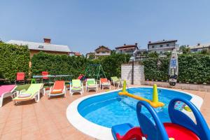 a swimming pool with chairs and a playground at Apartment Pool&Garden in Rijeka