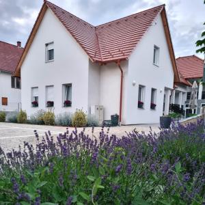 una casa con flores púrpuras delante de ella en Domb Apartmanok, en Sukoró