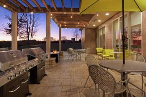 un patio al aire libre con mesa, sillas y parrilla en Home2 Suites by Hilton Woodbridge Potomac Mills, en Woodbridge