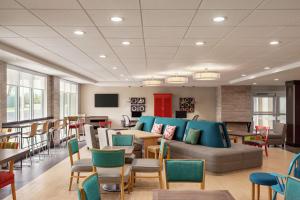 una sala de espera con sofá, mesas y sillas en Home2 Suites by Hilton Woodbridge Potomac Mills en Woodbridge