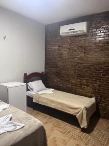 Cette chambre comprend 2 lits et un mur en briques. dans l'établissement Pousada Solar dos Lençóis, à Barreirinhas