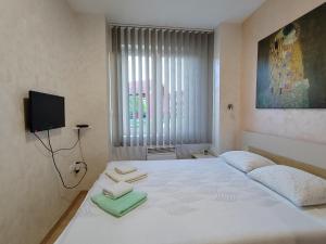 - une chambre avec un lit blanc et des serviettes dans l'établissement Apartments NANA, à Golubac