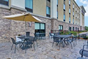 patio ze stołami, krzesłami i parasolem w obiekcie Hampton Inn Suites Ashland, Ohio w mieście Ashland