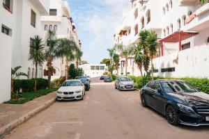 een rij auto's geparkeerd in een straat naast gebouwen bij Sea view malabata family only in Tanger