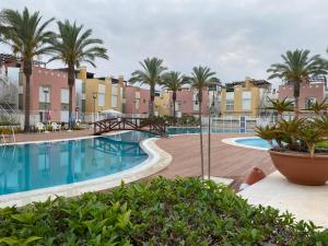 einen Pool in einem Resort mit Palmen und Gebäuden in der Unterkunft Lagunas Home, bajo con terraza al lado de la playa in Vera