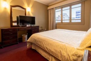 1 dormitorio con cama, espejo y TV en El Rey Palace Hotel, en La Paz