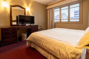 a bedroom with a bed and a mirror and a television at El Rey Palace Hotel in La Paz