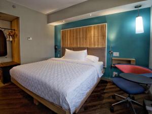 a bedroom with a large bed and a red chair at Tru By Hilton Oklahoma City Airport, Ok in Oklahoma City