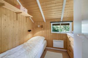 een kleine slaapkamer met een bed in een houten kamer bij Kildelodden14 in Ølsted