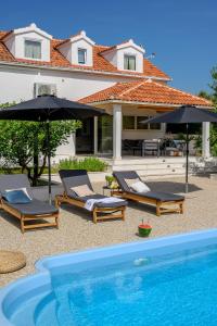 ein Pool mit zwei Stühlen und Sonnenschirmen neben einem Haus in der Unterkunft Villa Bellezza in Milna