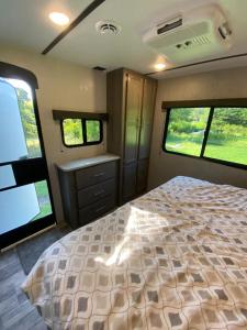 a bedroom with a bed and windows in an rv at Eden Farm RV Minutes from Salisbury in Eden
