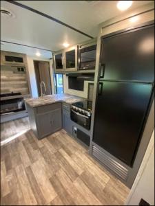 a kitchen with a black refrigerator and wooden floors at Eden Farm RV Minutes from Salisbury in Eden