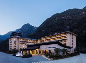 um grande edifício com uma montanha ao fundo em Hilton Sanqingshan Resort em Shangrao