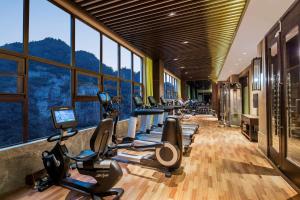 a gym with a row of treadmills and ellipticals at Hilton Sanqingshan Resort in Shangrao