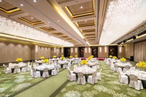 un salón de banquetes con mesas blancas y flores amarillas en Hilton Sanqingshan Resort en Shangrao
