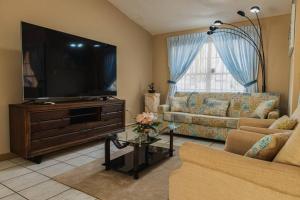 sala de estar con TV de pantalla plana y sofá en Blue Sky Residence Aruba, en Savaneta