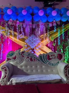 a stage with a white couch with purple and blue balloons at Hotel Maheshwari & Banquet Hall in Chamba