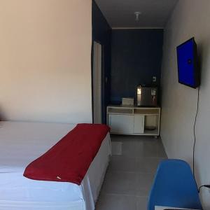 een slaapkamer met een bed met een rode deken en een televisie bij Hospedaria Salém in Soure