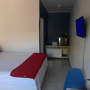 a bedroom with a bed with a red blanket and a tv at Hospedaria Salém in Soure +47 photos