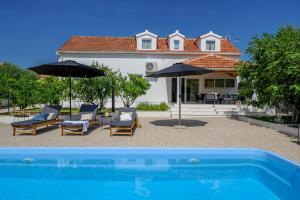 una piscina con sillas y sombrillas junto a una casa en Villa Bellezza en Milna