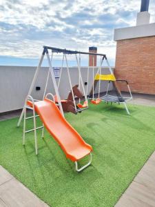a playground with an orange swing on a roof at Exclusivo mono para 4 personas in Luque