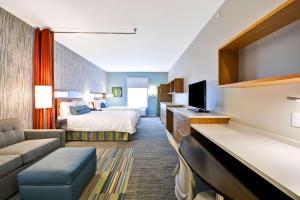 a hotel room with a bed and a couch at Home2 Suites By Hilton Evansville in Evansville