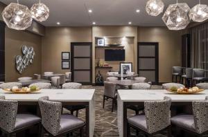 uma sala de jantar com mesas, cadeiras e lustres em Hampton Inn & Suites Bridgewater, NJ em Bridgewater