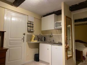 una pequeña cocina con armarios blancos y fregadero en studio, en Bauduen