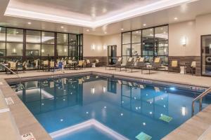 a swimming pool in a hotel with tables and chairs at Doubletree By Hilton Lafayette East in Lafayette