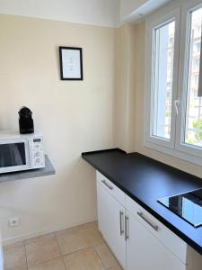 een keuken met een zwart aanrecht en een magnetron bij Cool Appart sur Croisette Palm Beach in Cannes