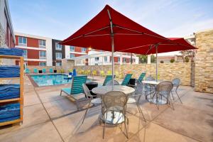 a patio with a table and chairs and a red umbrella at Home2 Suites By Hilton Livermore in Livermore