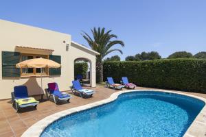 una piscina con sillas y una sombrilla junto a una casa en Villa Menorca Cleo by Mauter Villas, en Cala Blanca