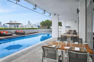 uma área de refeições exterior com uma piscina, uma mesa e cadeiras em Hilton Garden Inn Singapore Serangoon em Singapura