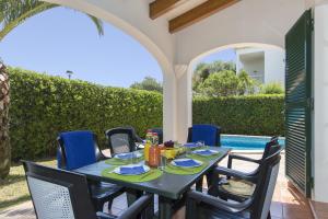 a table and chairs on a patio with a pool at Villa Menorca Cleo by Mauter Villas in Cala Blanca