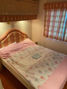 a bedroom with a bed with a pink blanket on it at ALBA Pelnik domki holenderskie in Pelnik