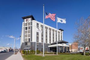 duas bandeiras americanas no topo de um edifício branco em DoubleTree by Hilton Boston Logan Airport Chelsea em Chelsea